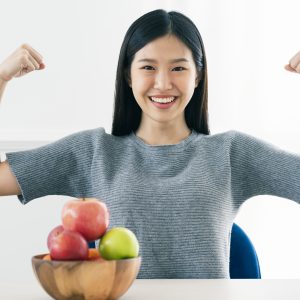 strong healthy asian beautiful woman hand show fresh fruit apple with action fit and firm posing healhty food diet ideas concept